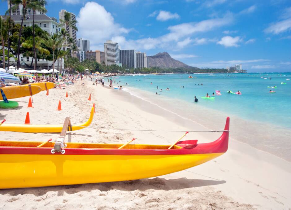 Outrigger canoes on Waikiki Beach with Diamond Head Mountain in the background.